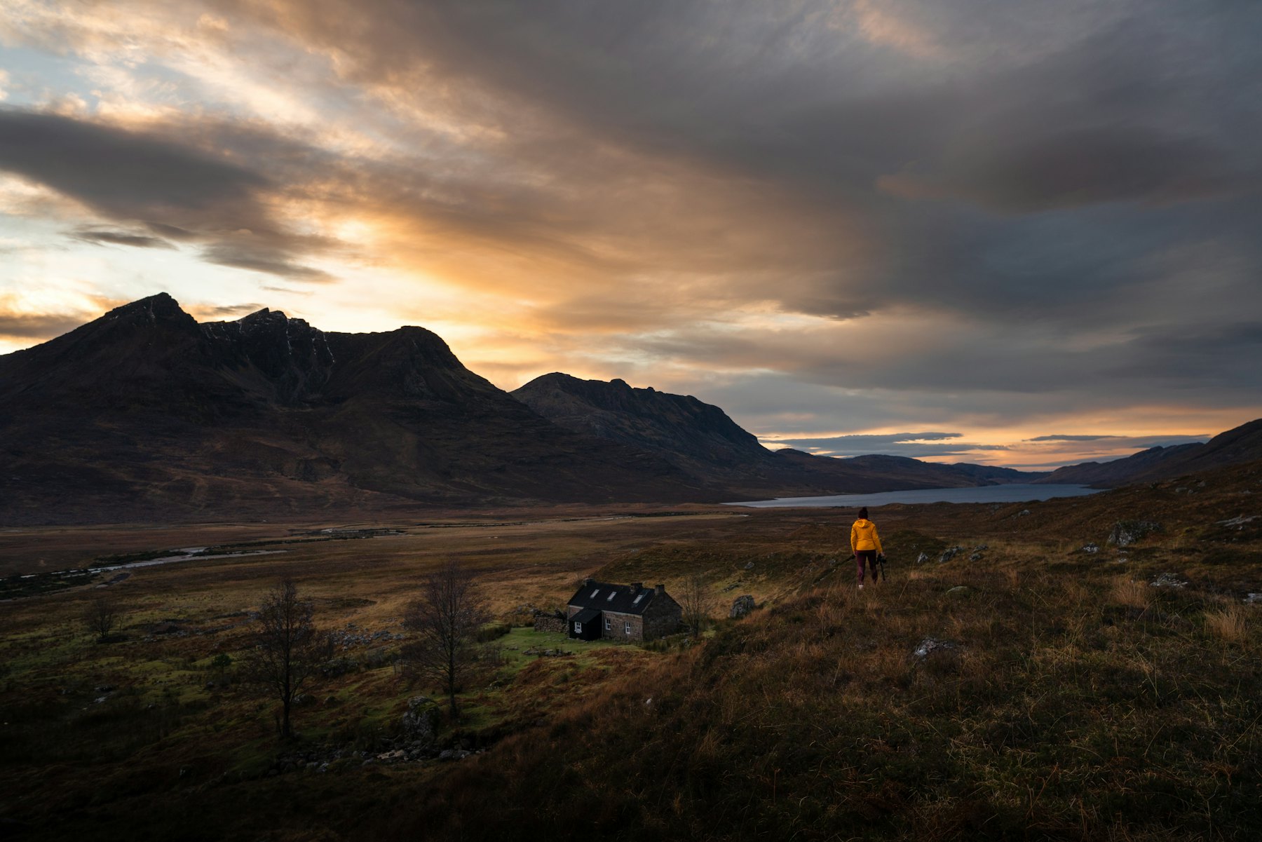 Shenavall Bothy at sunset in the Scottish Highlands, a low stone shelter under the hills